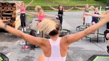 Gruppe von Frauen, die draußen auf Trampolinen trainieren.