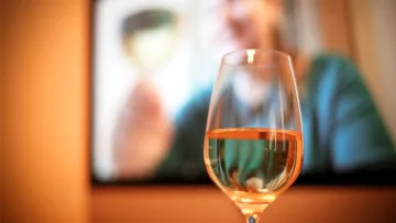 Wine glass in front of blurry screen.