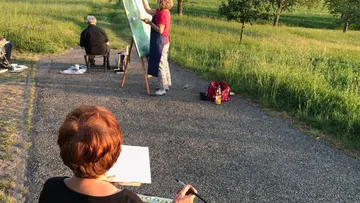 Menschen, die draußen auf einem sonnigen Pfad malen.