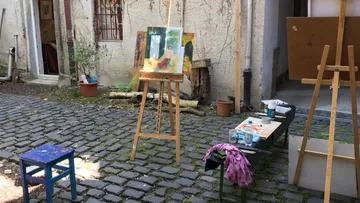 Outdoor art studio with easels and paintings.