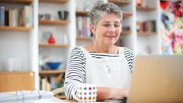 Smiling woman using laptop in home office.