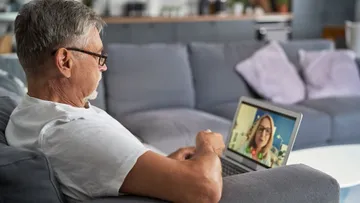 Mann, der auf dem Laptop im Wohnzimmer per Video chattet.