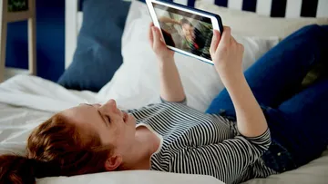 Person video calling on tablet in bed