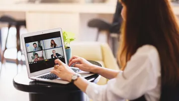 Frau am Laptop, die drinnen einen Videoanruf führt.