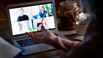 Person im Videoanruf mit vier Personen am Laptop.