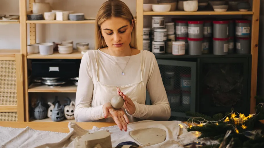 Woman shaping clay in art studio.