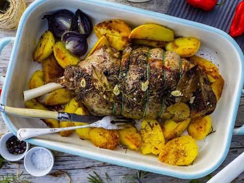Geröstetes Fleischgericht auf Kartoffeln, dekoriert mit Kräutern.