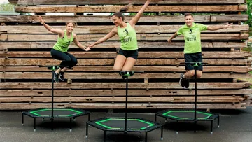 Drei Personen springen draußen auf Minitrampoline.