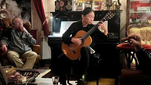 Person, die Gitarre in einer rauchgefüllten Lounge spielt.