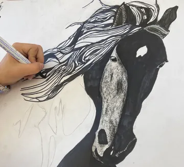 Hand sketching a horse with flowing mane.