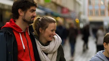 Smiling couple walking in busy street.