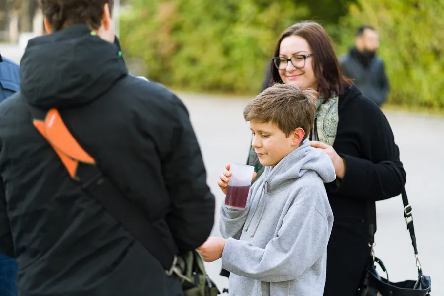 Boy drinks juice, people in park setting.