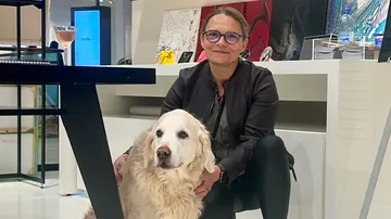 Person crouching beside a large white dog indoors.