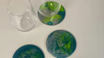 Glass cups on colorful coasters, white background.