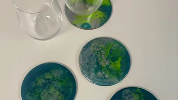 Vier blaugrüne Untersetzer mit Gläsern auf dem Tisch.