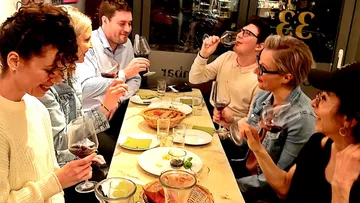 Gruppe von Menschen, die Wein an einem Tisch genießen.
