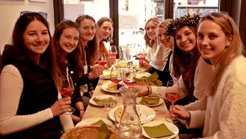 Gruppe von Frauen, die eine Mahlzeit mit Wein genießen.