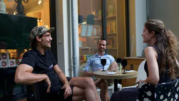 Three people enjoy drinks in a cozy cafe.