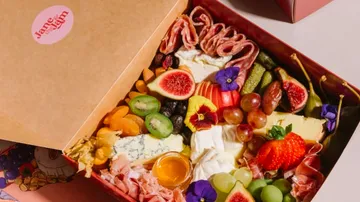 Charcuterie box with fruits, cheeses, and meats.