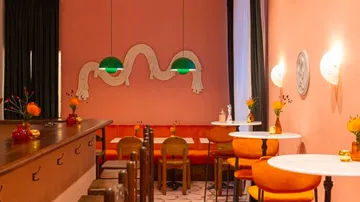 Stylish cafe with pink walls and orange seating.