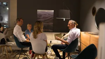 Gruppe sitzt im modernen Wohnzimmer und unterhält sich.