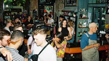 Überfüllte Bar mit geselligen Leuten und Barkeeper