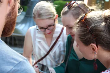 Group of people looking at a phone outdoors.