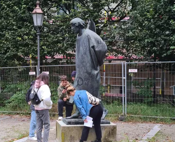 People examining metal statue in park.