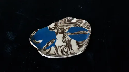 Marmorierte Keramikschale mit blauem Blattmuster.