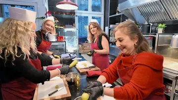 Gruppe kocht zusammen, bereitet frische Zutaten in Küche vor.