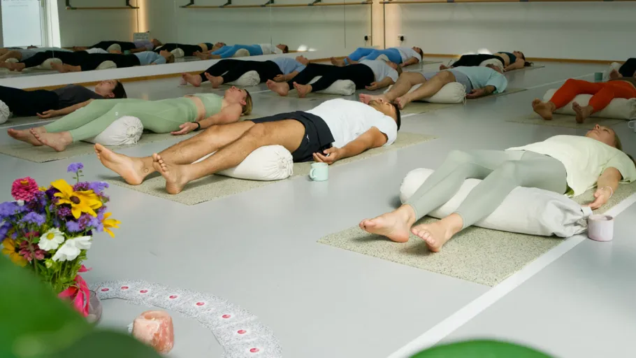 People lying on mats in yoga studio.