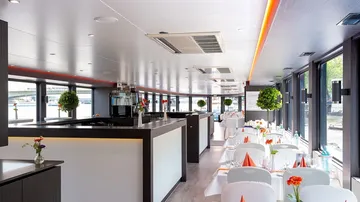 Elegantes Restaurant mit Tischen, das Licht reflektiert Wasser.