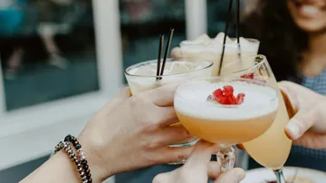 Hands holding cocktails in toast gesture.