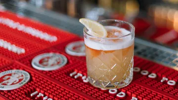 Cocktail with lemon slice on bar mat.