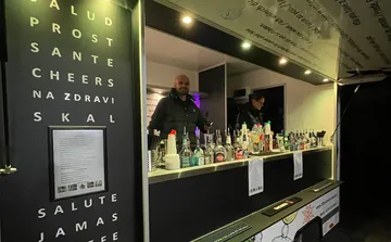 Bar counter with multiple bottles and people behind.