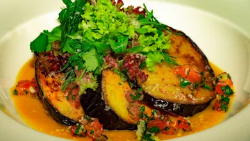 Gegrillte Auberginen mit frischen Kräutern in einer Schüssel.