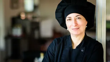 Chef in black uniform smiling indoors.