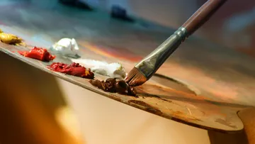 Brush mixing paint on artist's palette.