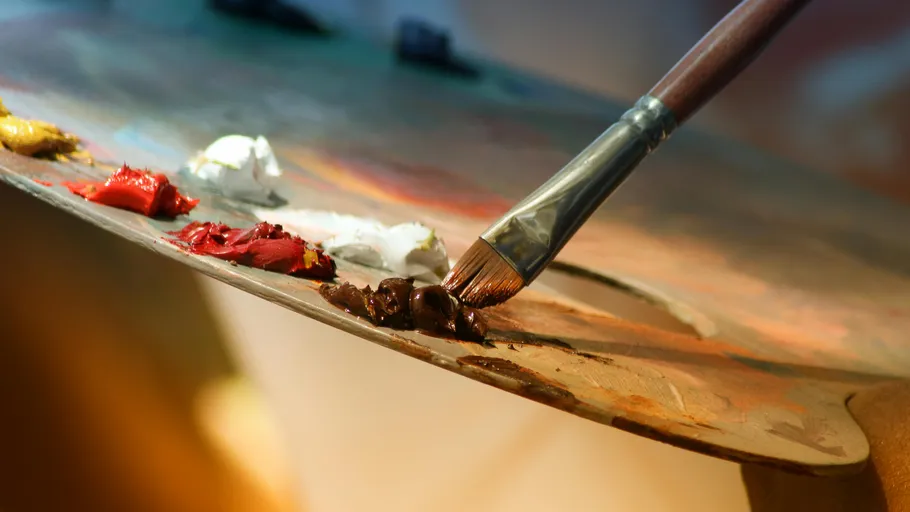 Brush mixing paint on artist's palette.