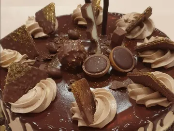 Chocolate cake decorated with various sweets and cream.