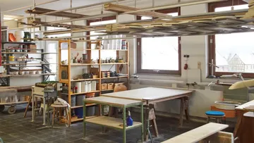 Holzwerkstatt mit Tischen und Regalen.