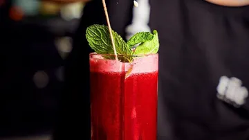 Red juice with mint garnish, being poured.