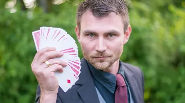 Mann hält im Freien gefächerte Spielkarten in der Hand.