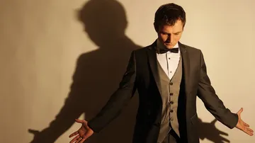 Man in formal suit casting shadow on wall.