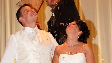Bride and groom smiling with confetti falling.