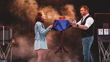 Two people performing a magic trick on stage.