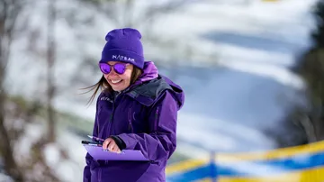 Eine Frau in lila Kleidung hält die Zwischenablage in der verschneiten Gegend.