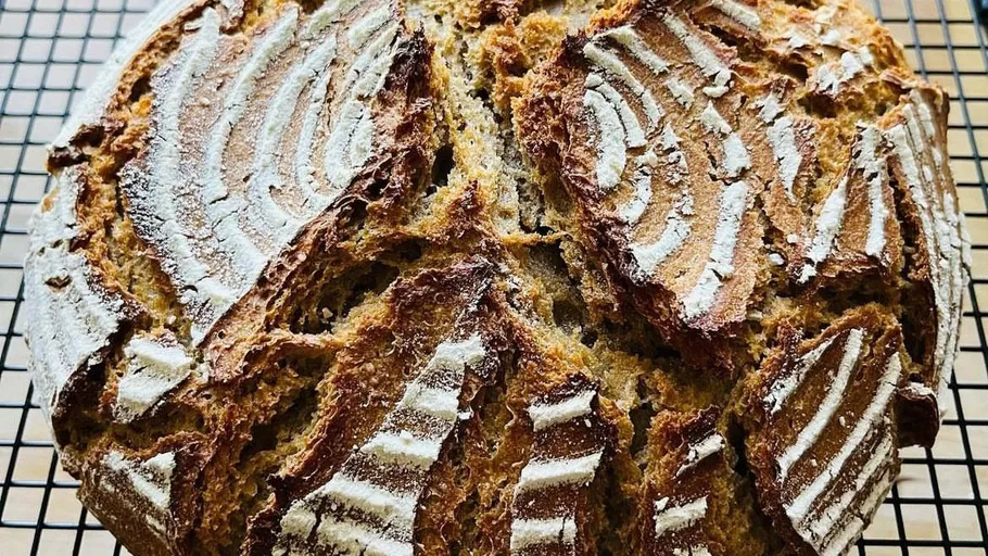 Loaf of sourdough bread on cooling rack.