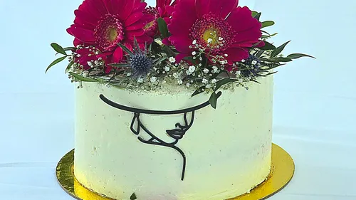 Floral-decorated cake with face illustration.