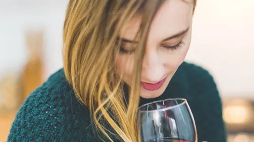 Woman smelling wine in glass indoors.